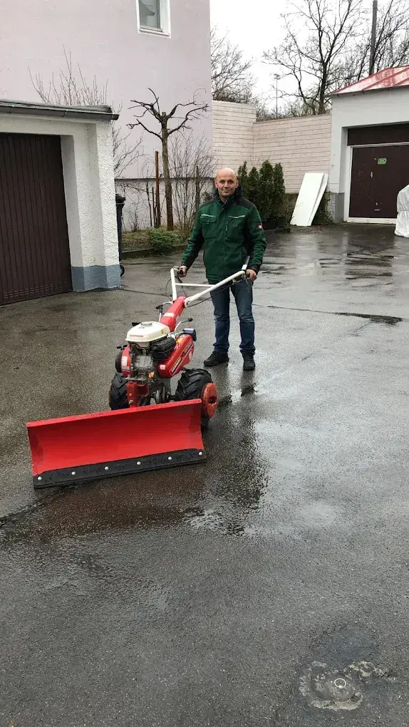 Mitarbeiter mit Motor-Schneepflug für Gehwege und Einfahrten